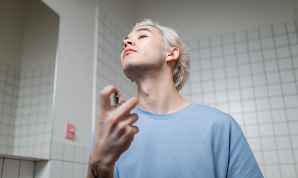 Hombre aplicándose perfume durante su rutina diaria